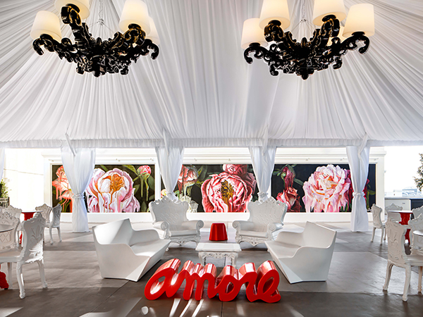 a white tent with white chairs and a red table
