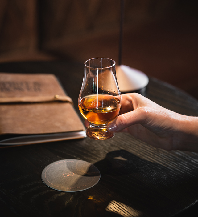 a hand holding a glass of alcohol
