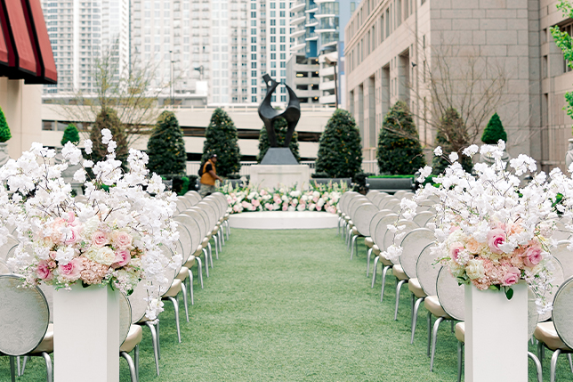 a row of chairs with flowers in front of a statue