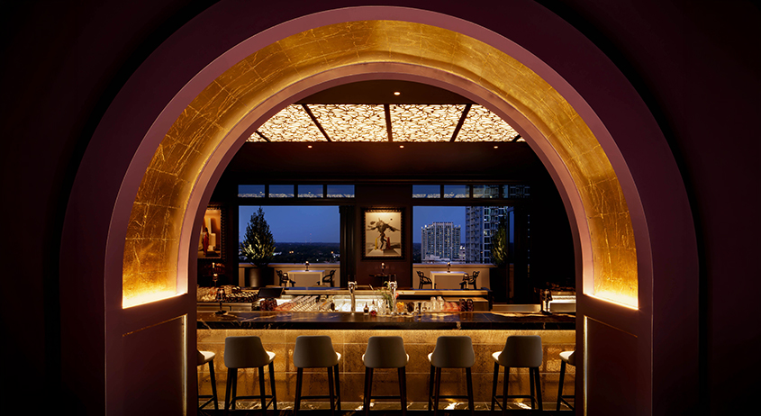a bar with stools and chairs in a room with a view of a city