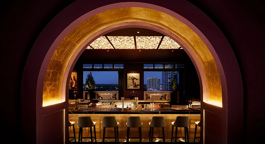 a bar with stools and chairs in a room with a view of a city
