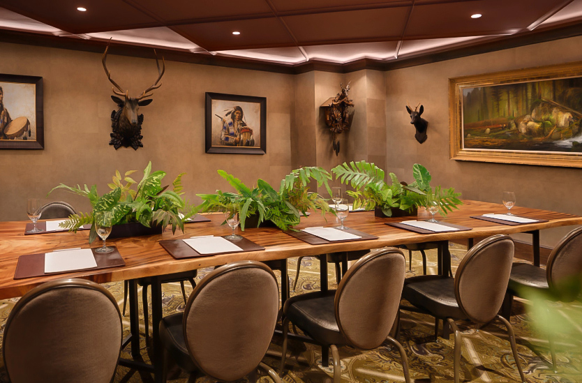 a room with a table with plants and a deer head mounted on the wall