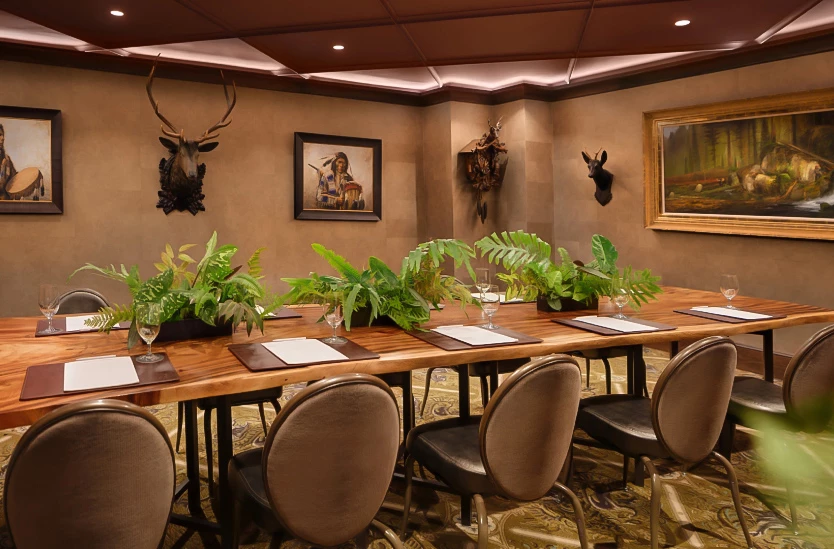 a room with a table with plants and a deer head mounted on the wall