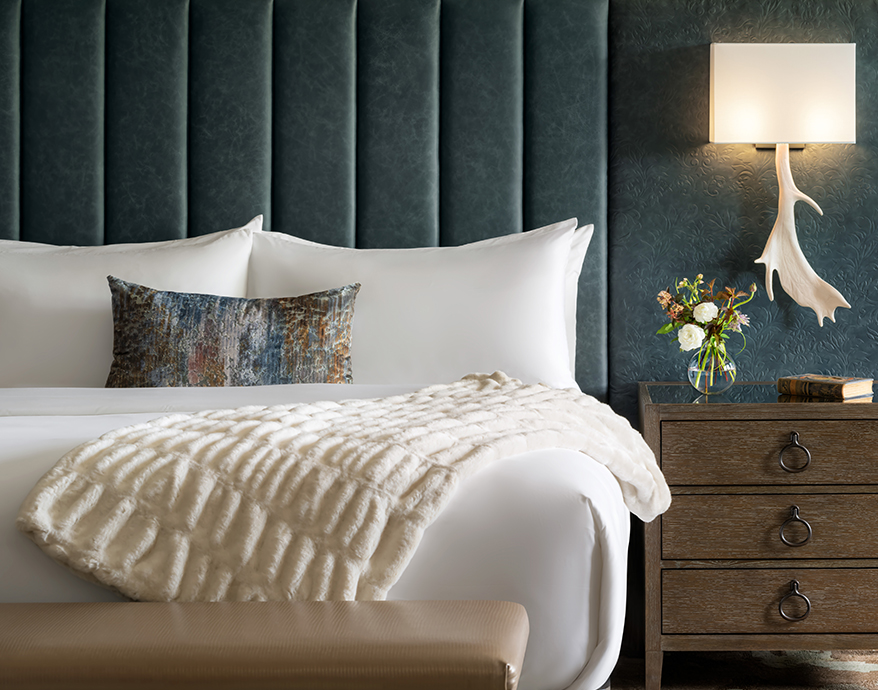 a bed with a white blanket and a lamp next to a nightstand