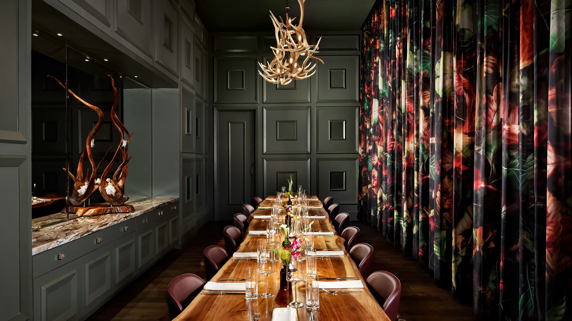 a long table with flowers and antlers in a room