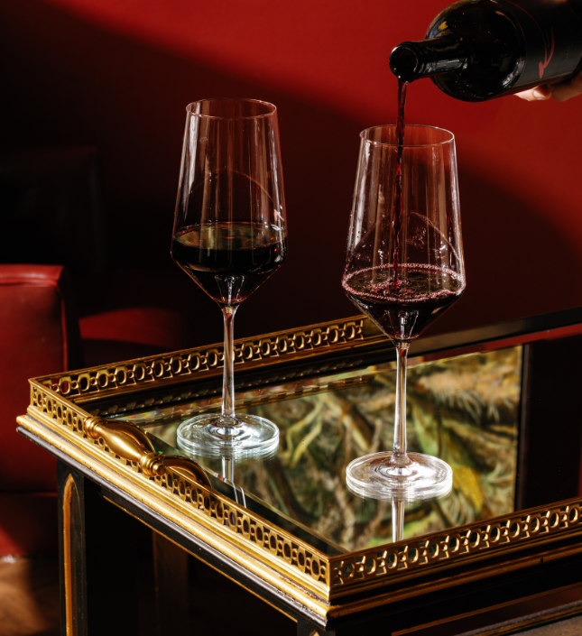 a person pouring wine into two wine glasses