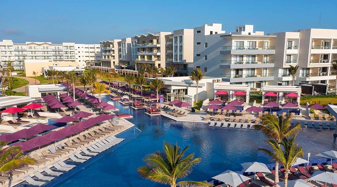 a pool with umbrellas and chairs in front of buildings
