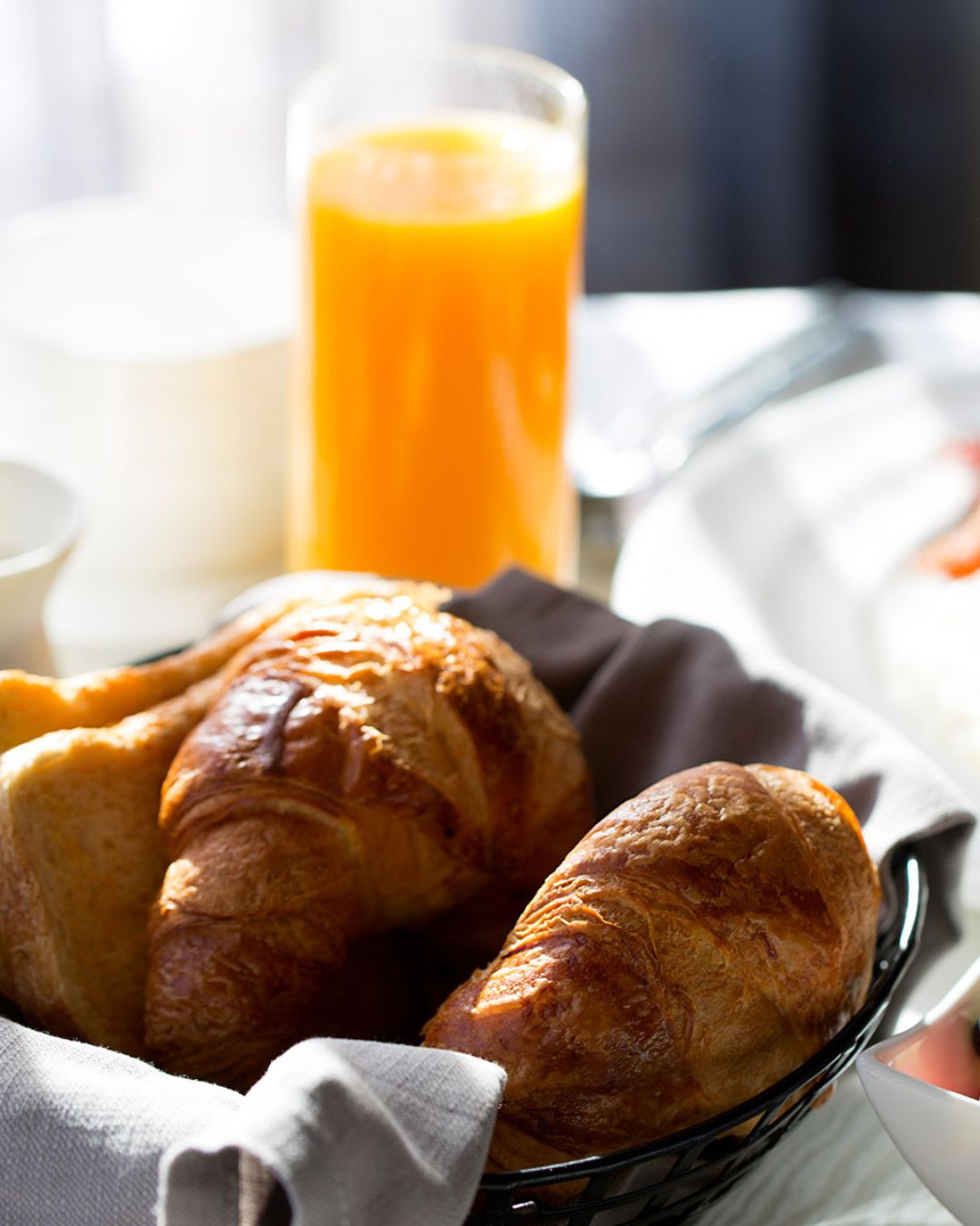 a basket of croissants and a glass of orange juice