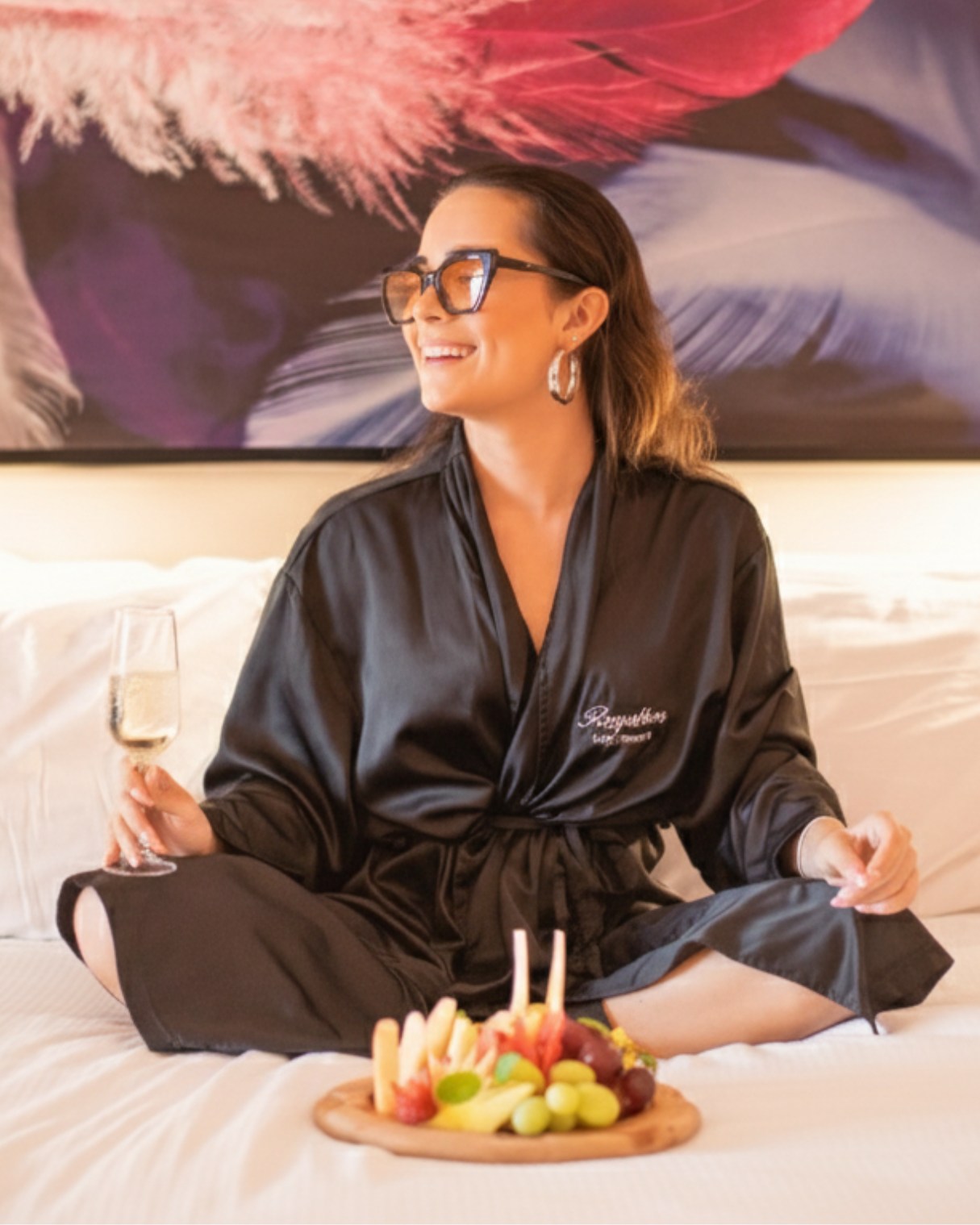 a woman sitting on a bed with a glass of wine