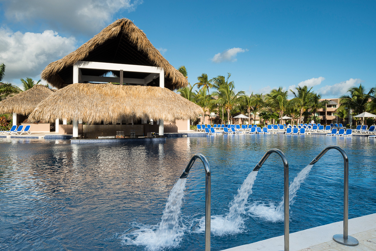 a pool with a thatched roof and a hut