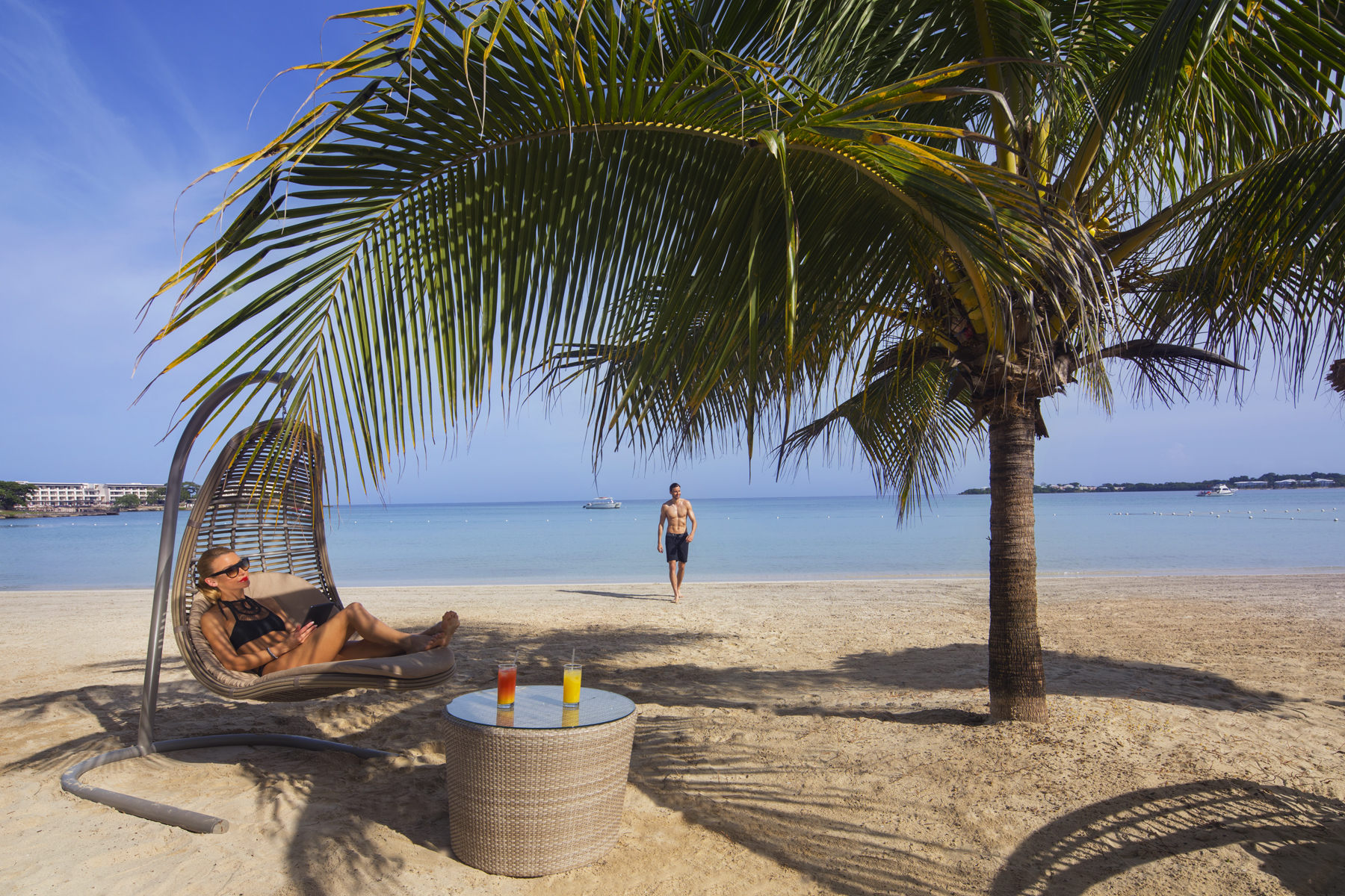 a couple of people sitting under a palm tree on a beach