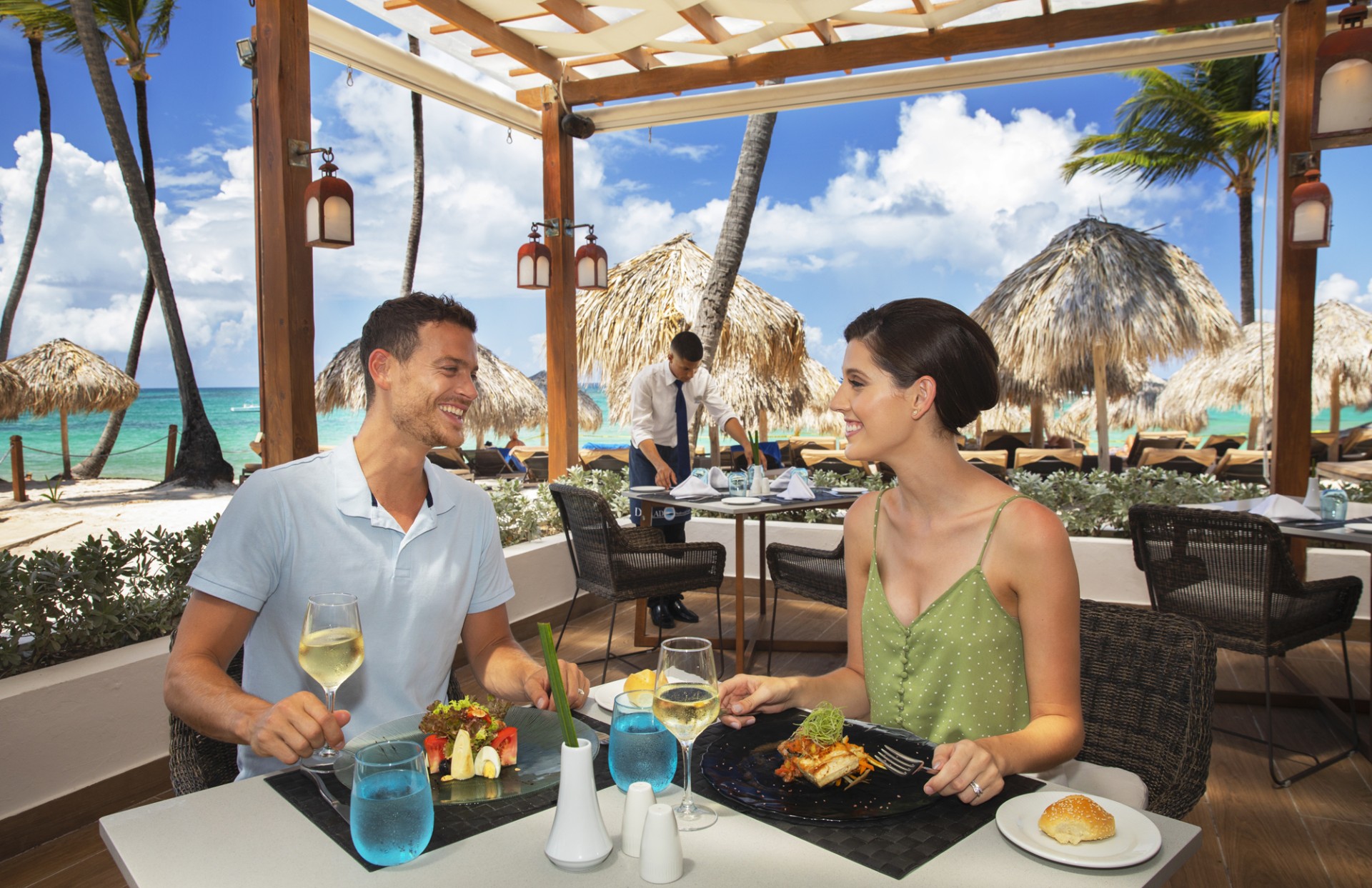 a man and woman sitting at a table with food and drinks