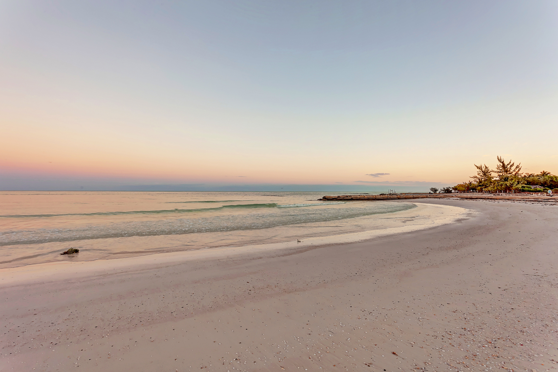 a beach with a body of water and a pier