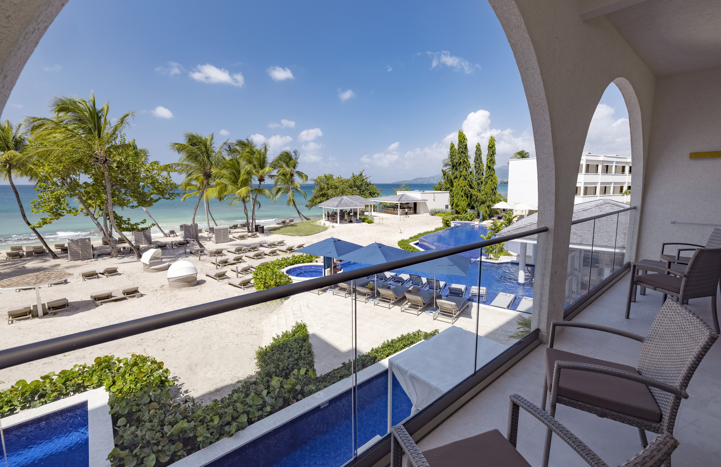 a balcony with chairs and a pool on the beach