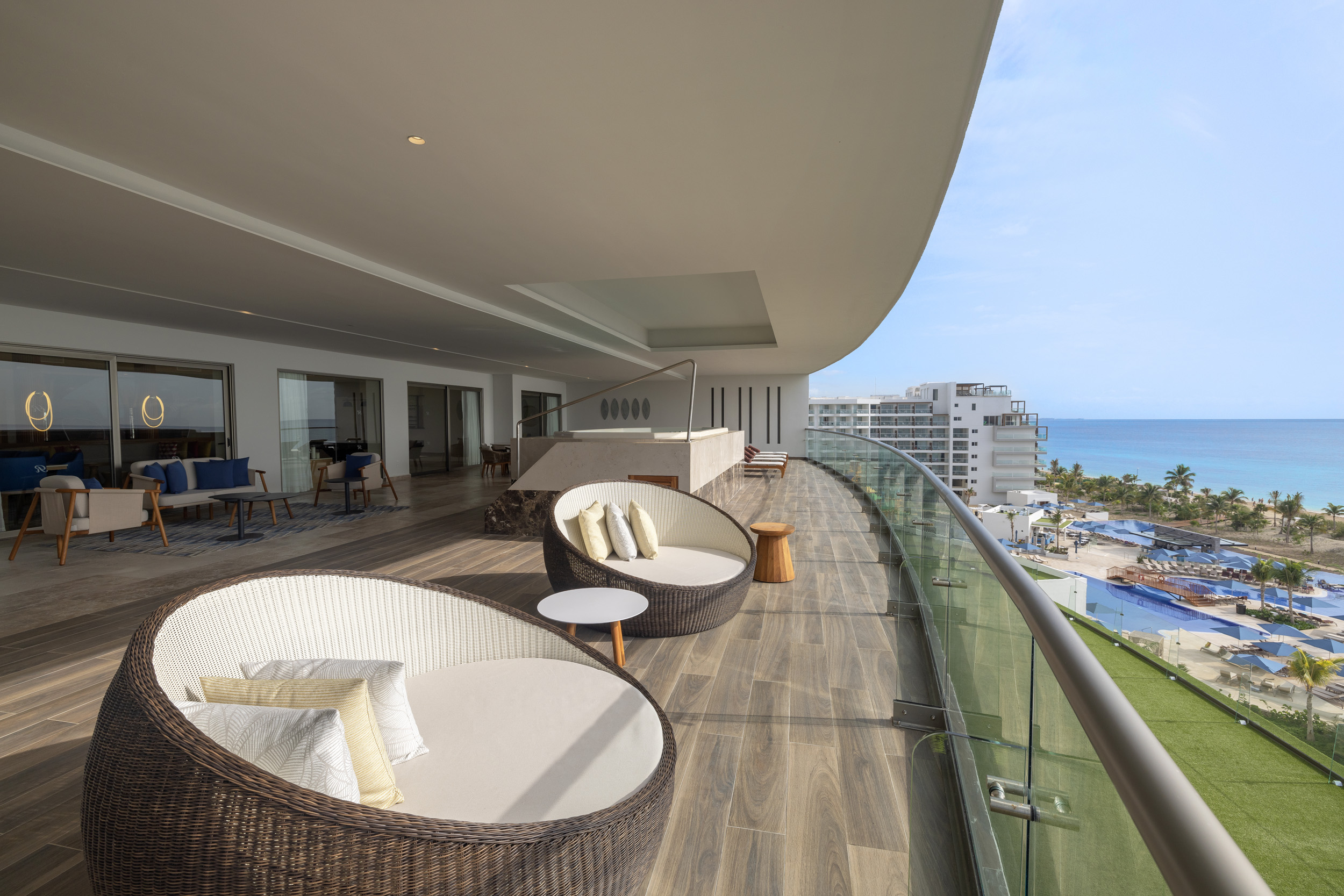 a deck with chairs and tables on a balcony overlooking a beach
