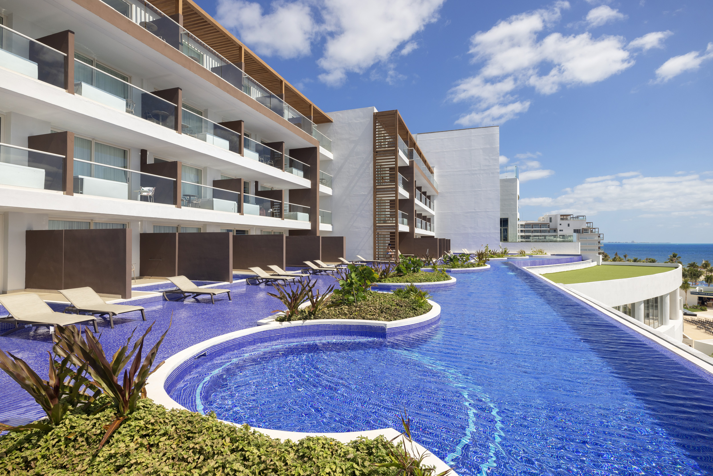 a pool with lounge chairs and a pool in front of a building