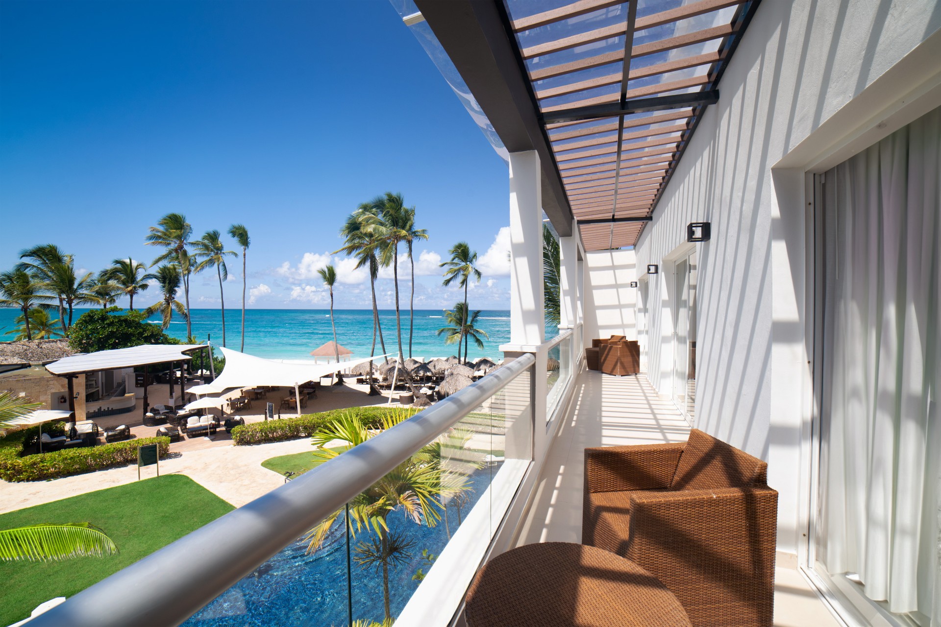 a balcony with chairs and a pool overlooking the ocean