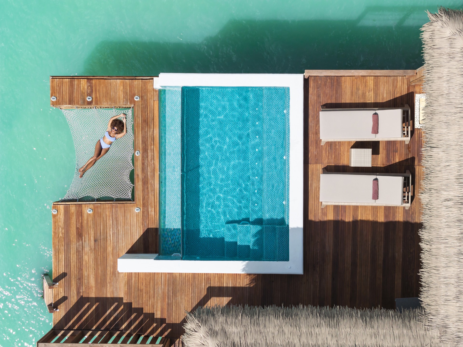 a woman lying on a hammock next to a pool