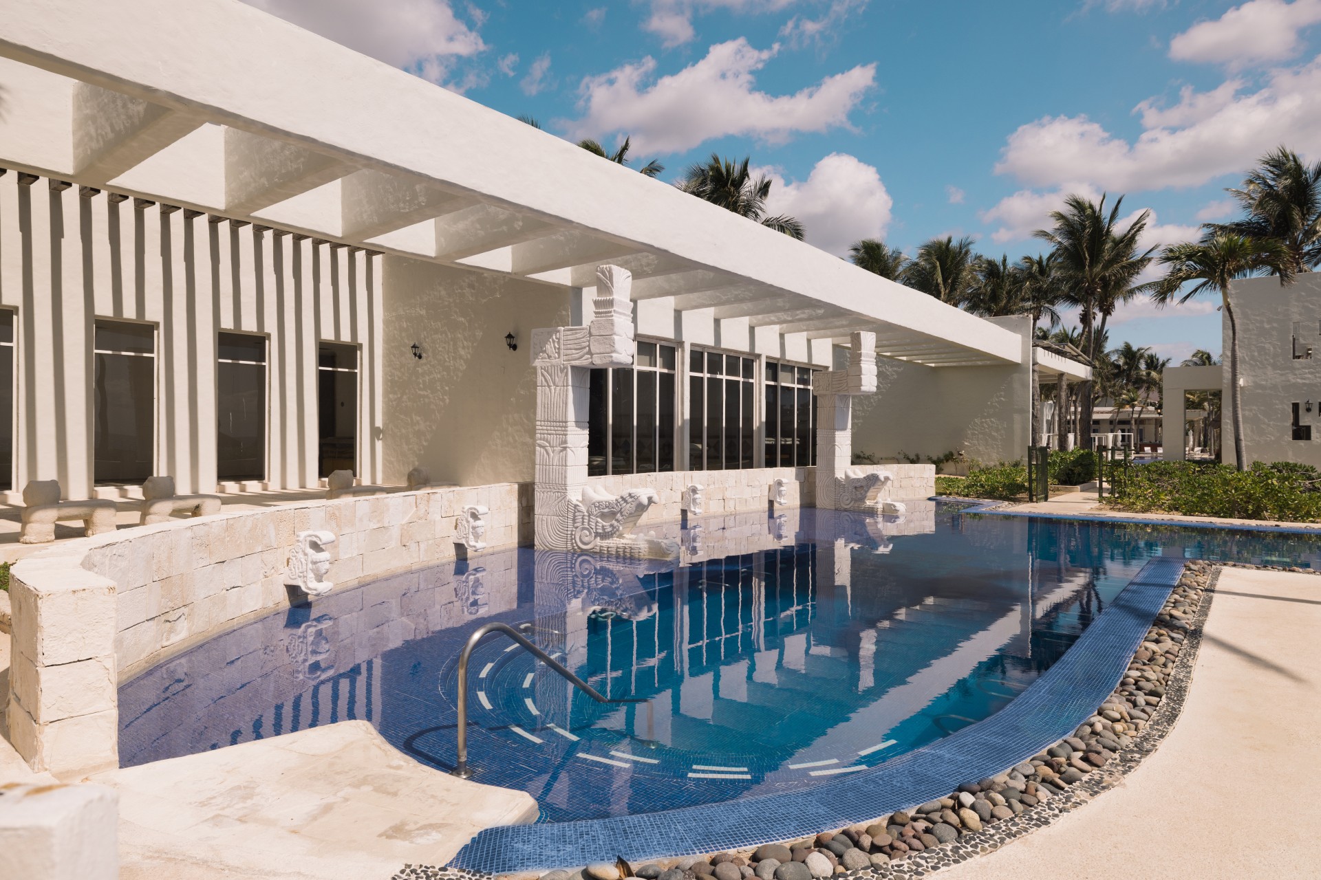 a pool with a white building and palm trees