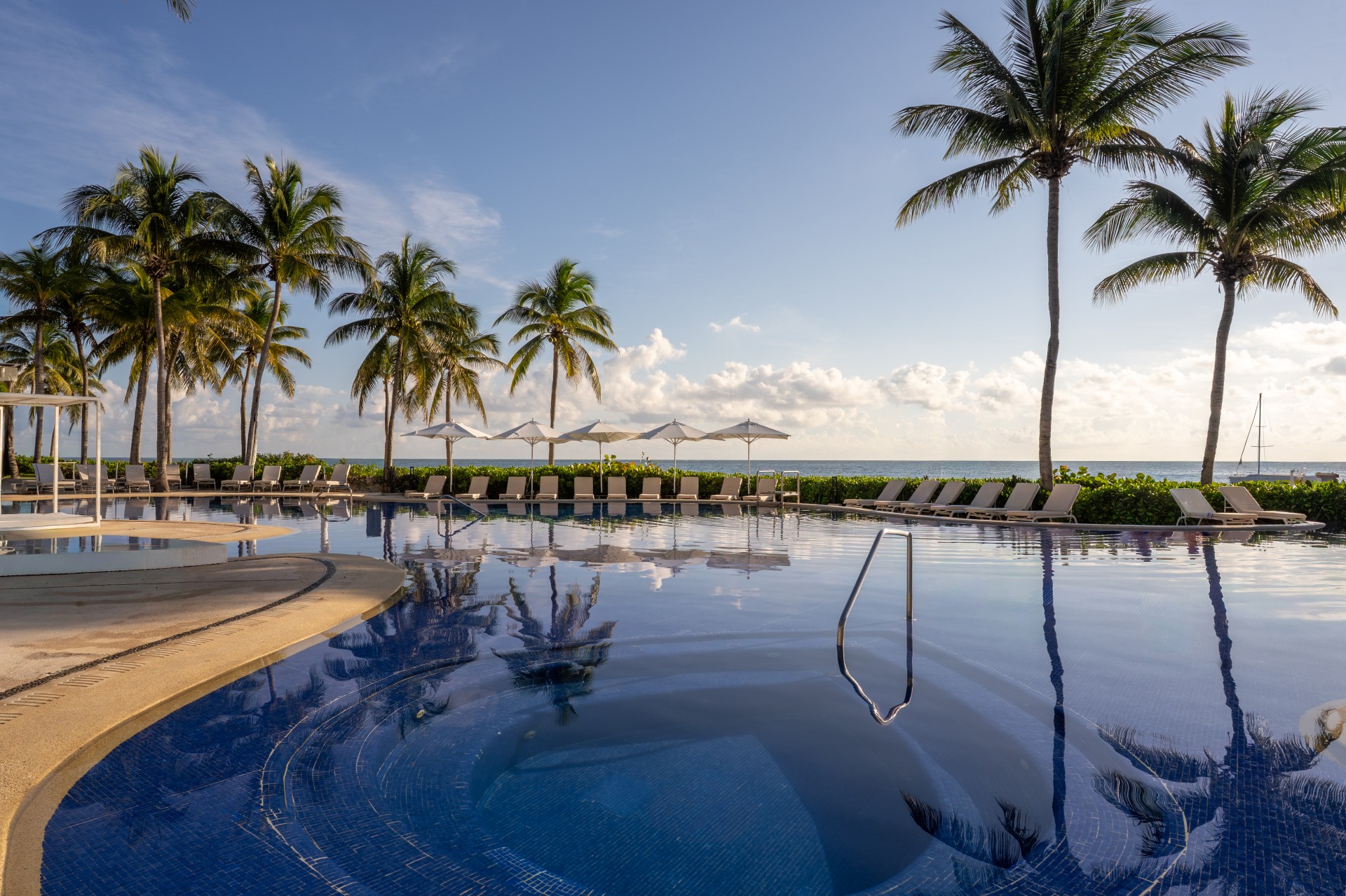 a pool with chairs and umbrellas by the ocean