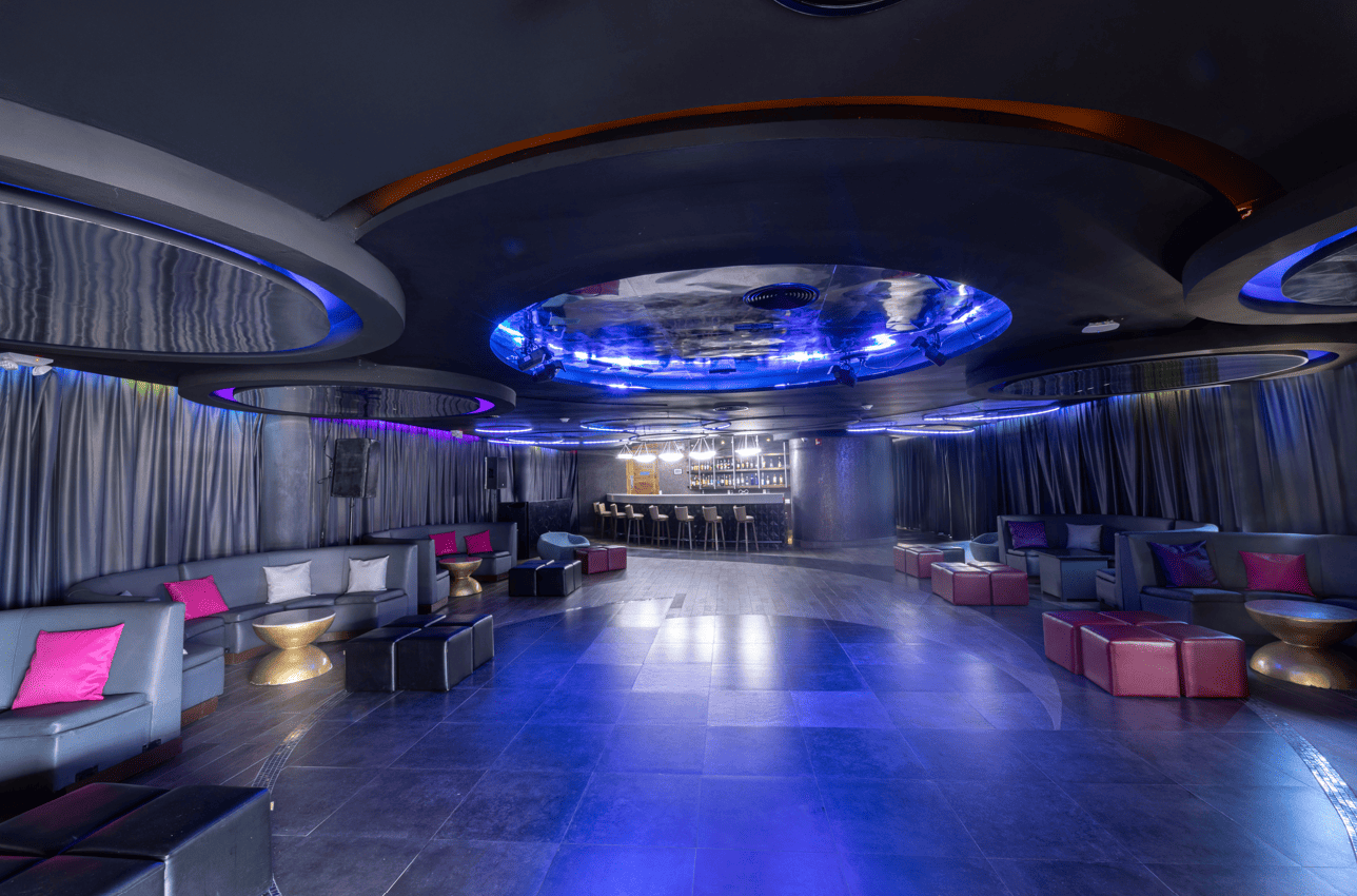 a room with a large round ceiling and a bar with stools and tables