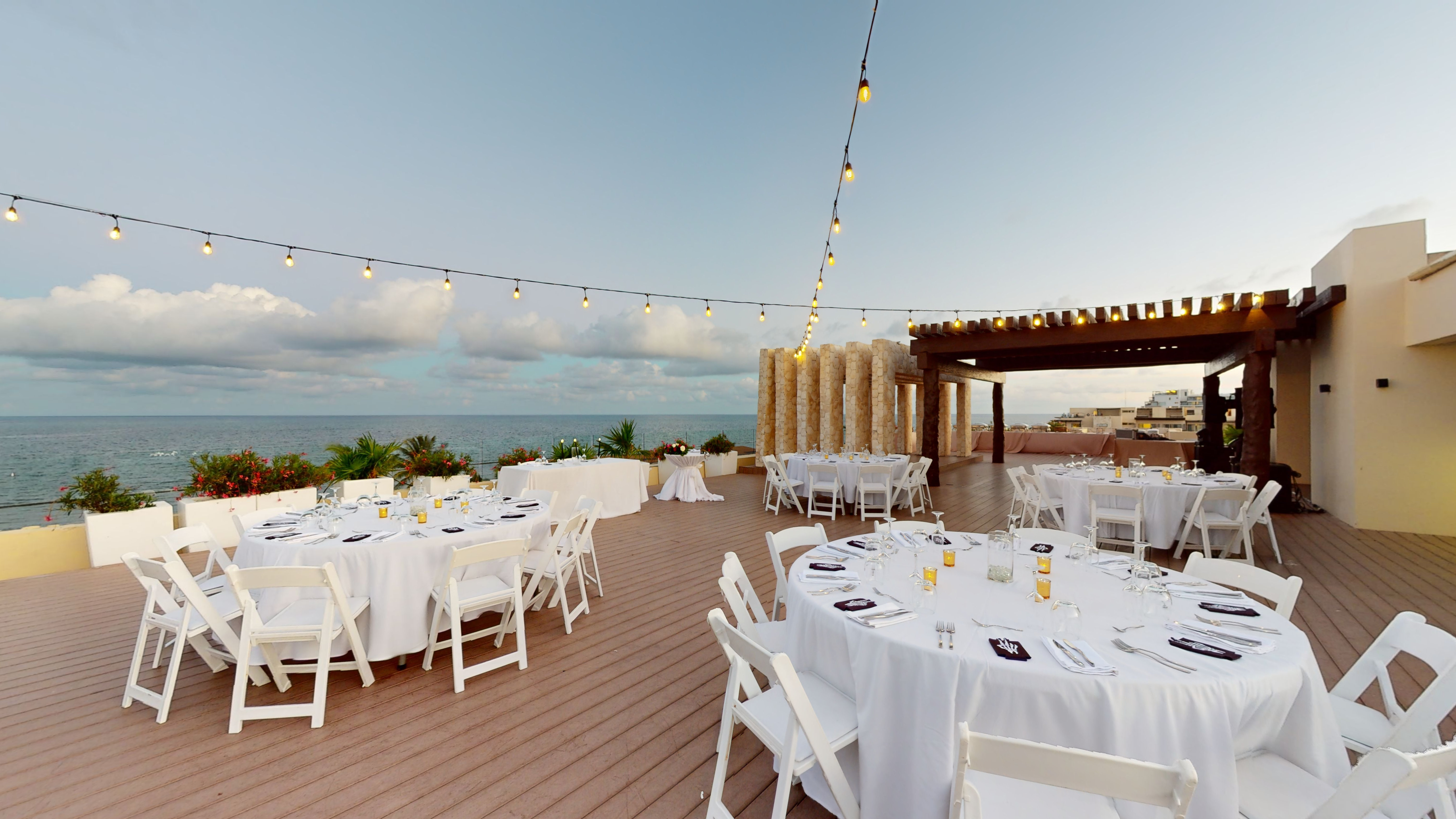 a group of tables set up on a deck with a view of the ocean