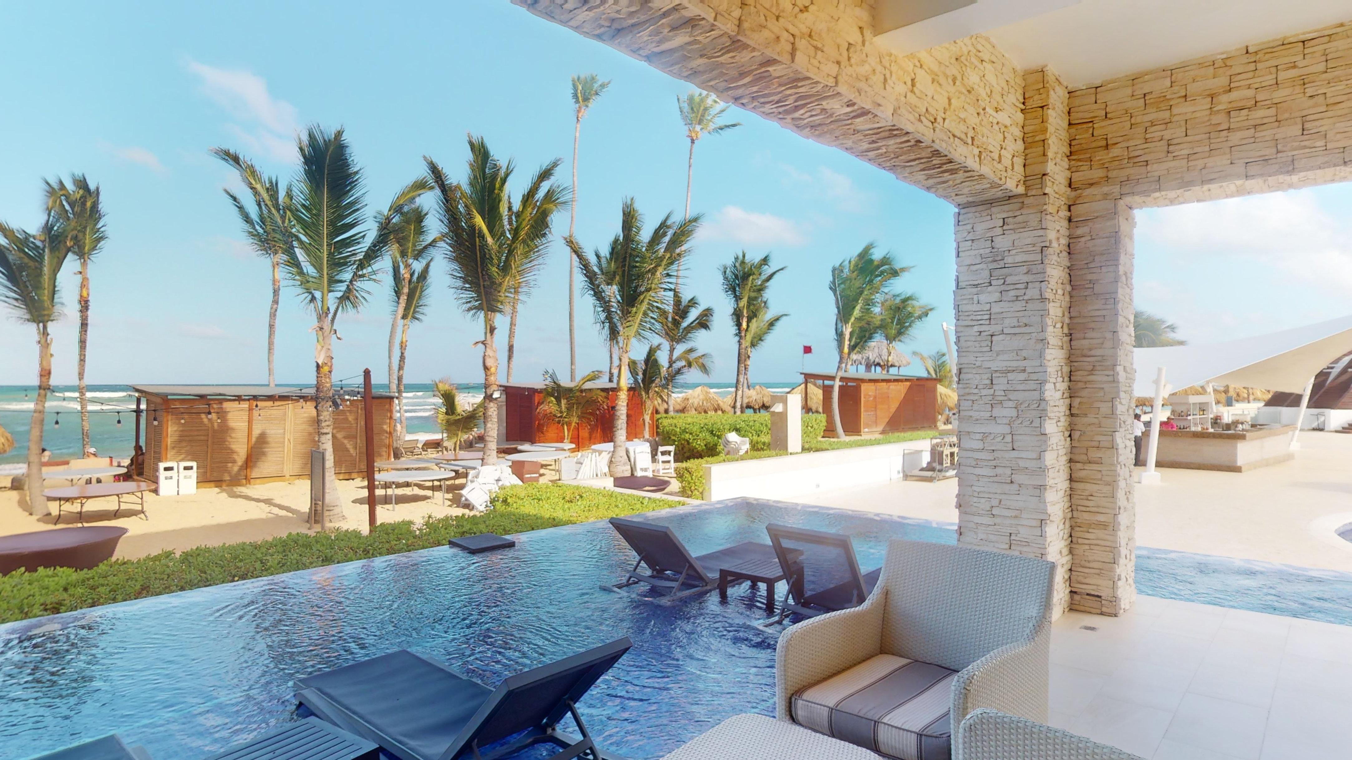 a pool with chairs and a beach view