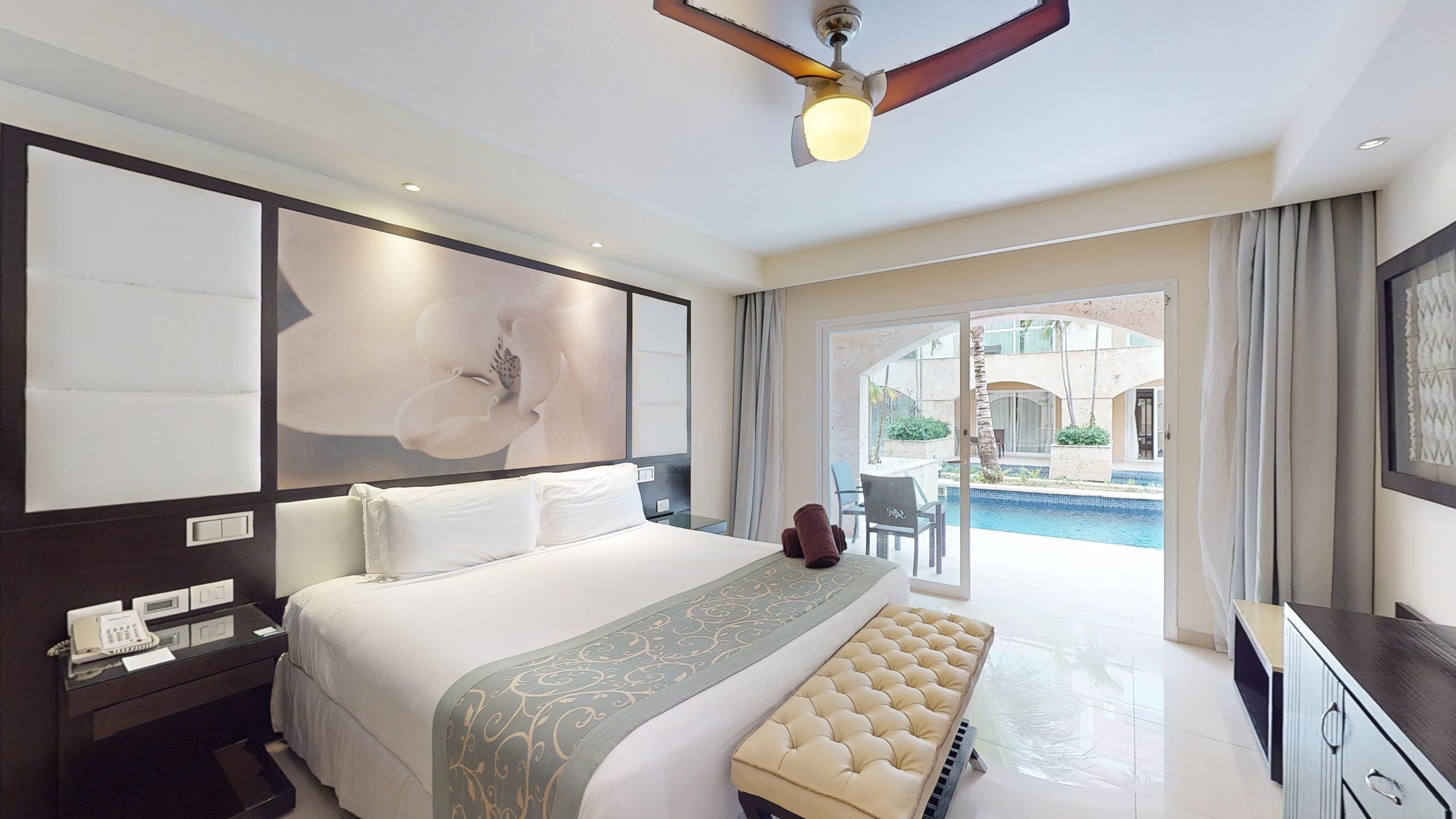 a bed with a fan and a picture on the wall