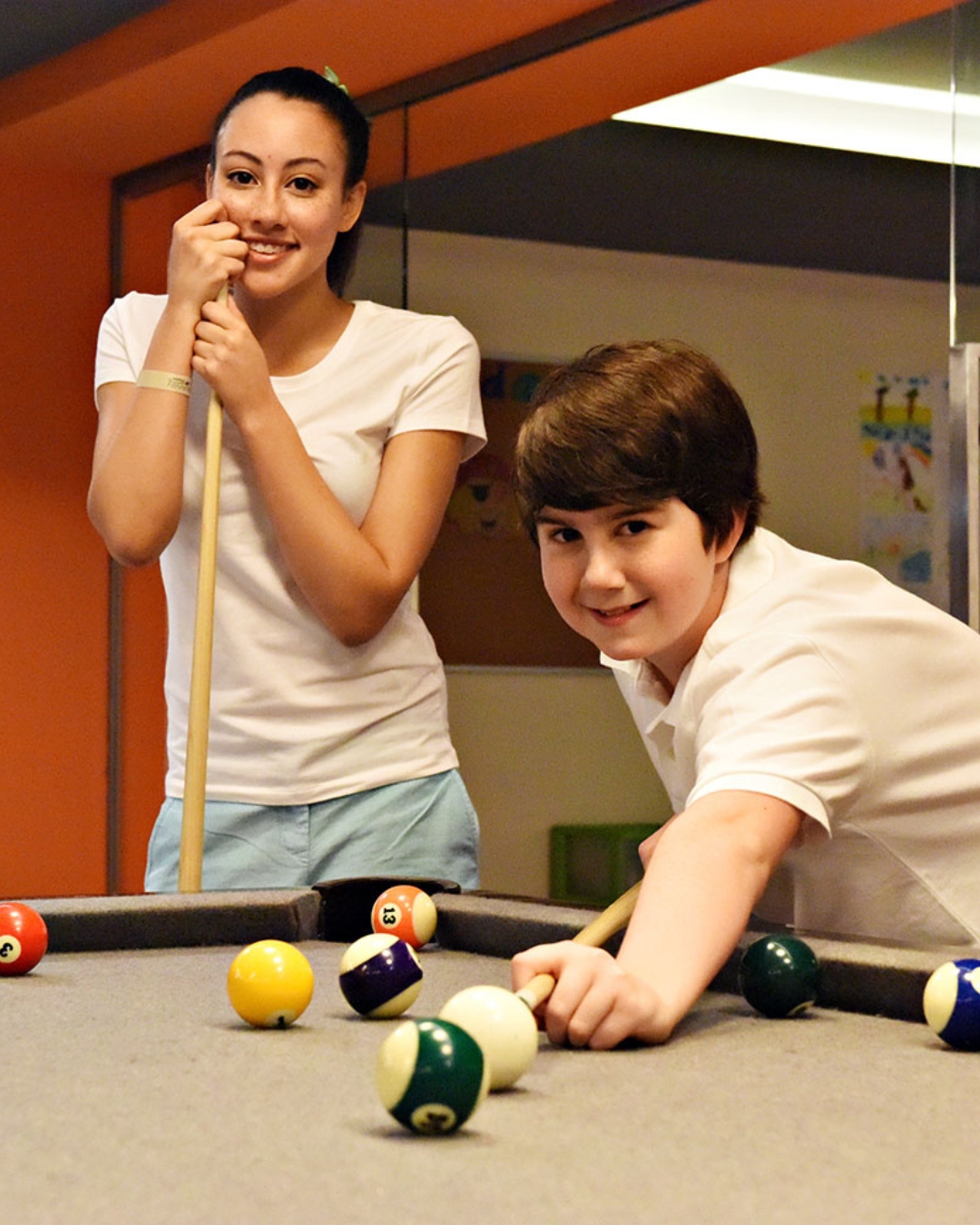 a boy and girl playing pool