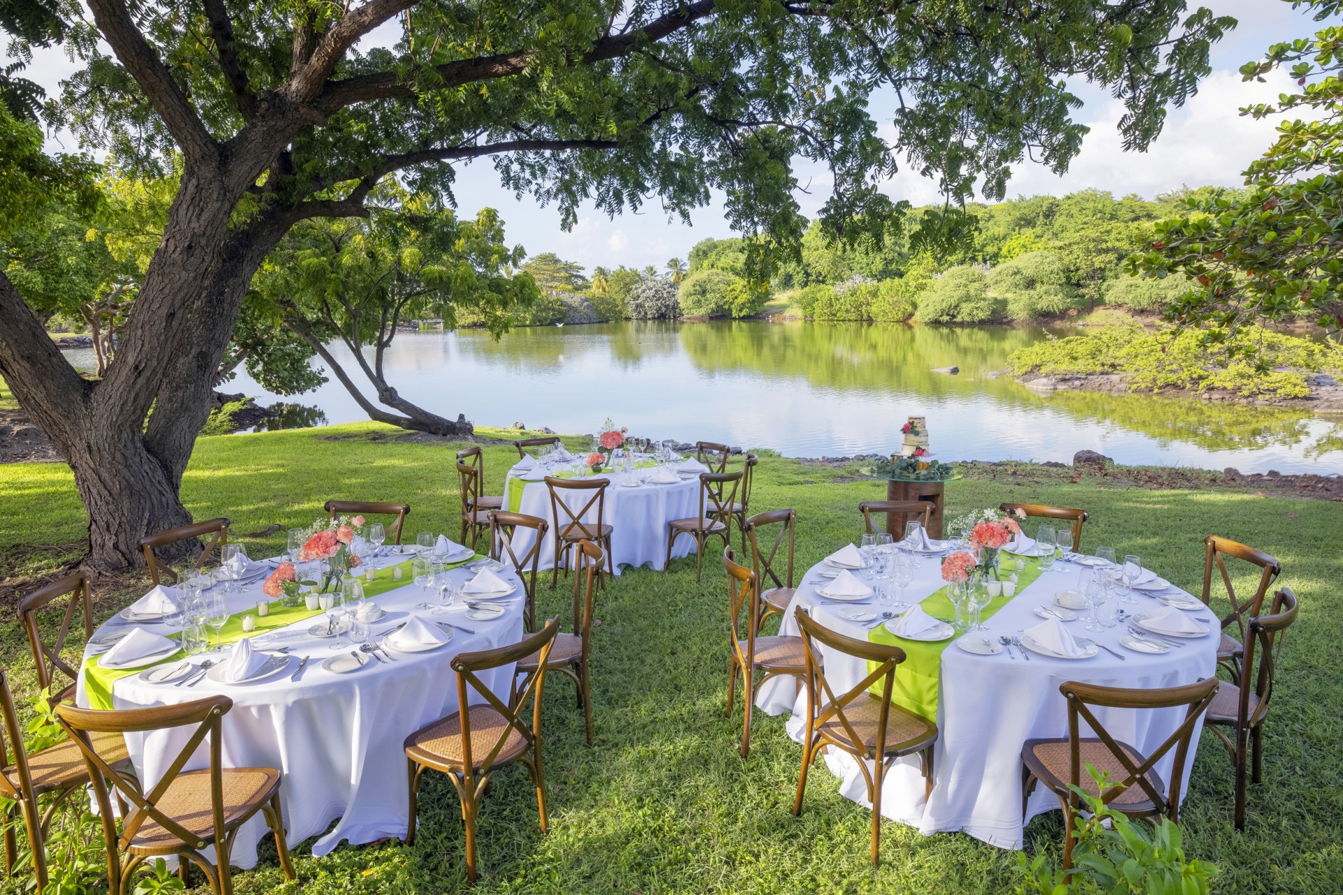 a group of tables set up in a grassy area with a lake and trees