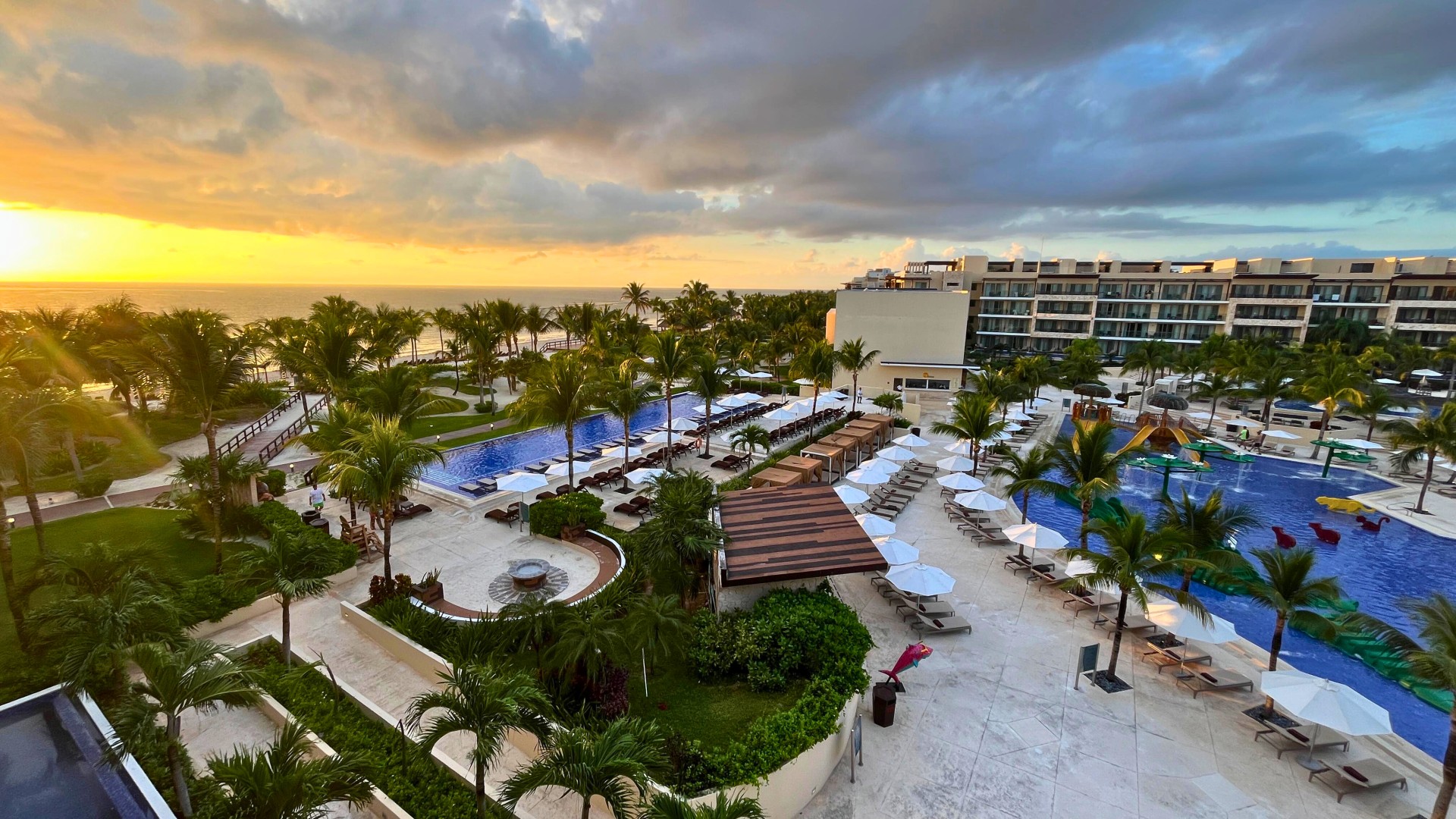 a pool and palm trees with a building in the background