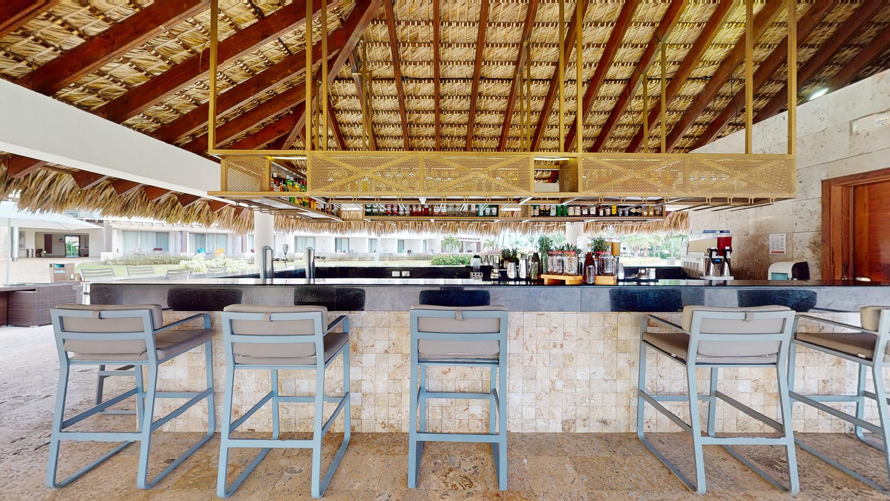 a bar with chairs and a straw roof