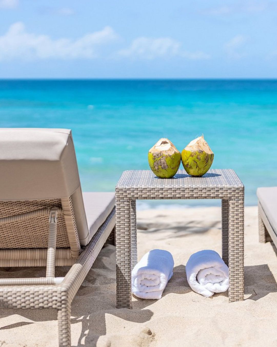 two coconuts on a table next to towels on a beach
