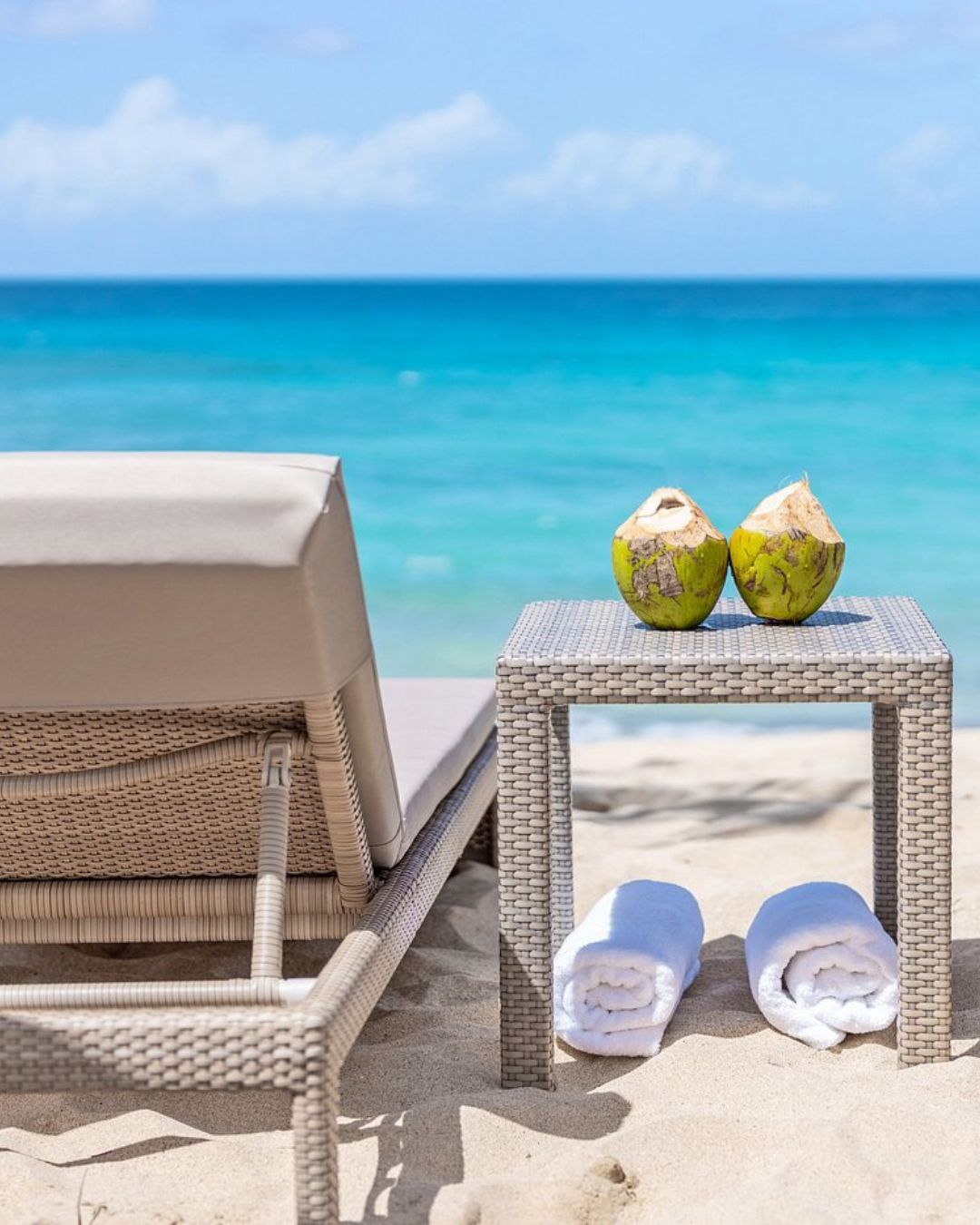 a beach chair and a table with towels on the sand