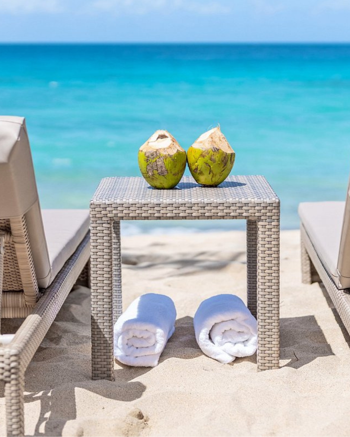 two coconuts on a table with towels on the beach