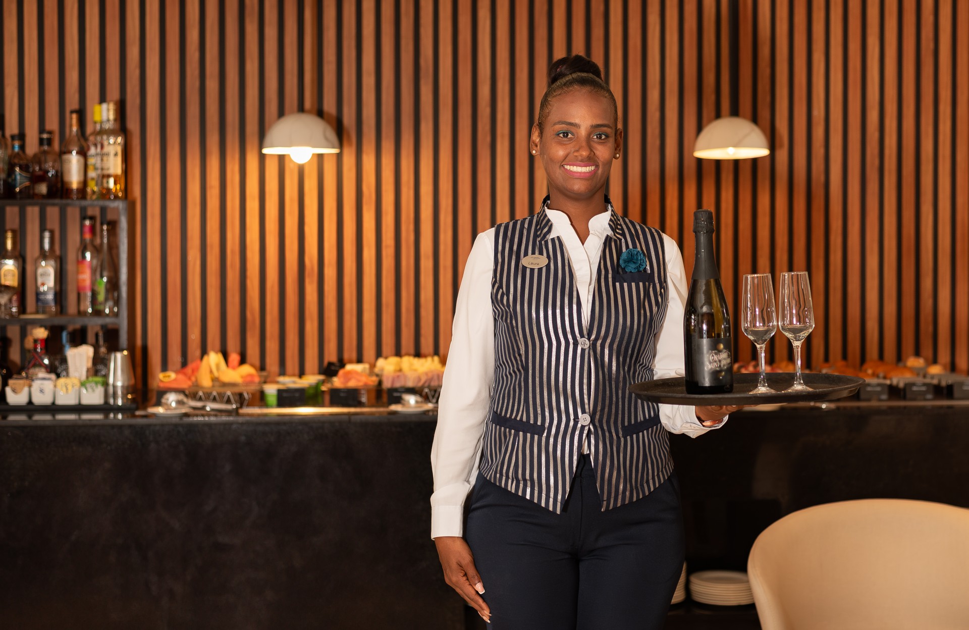 a woman holding a tray of wine and glasses
