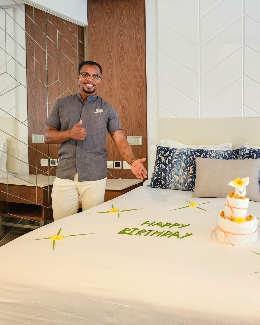 a man standing next to a bed with a cake and flowers on it