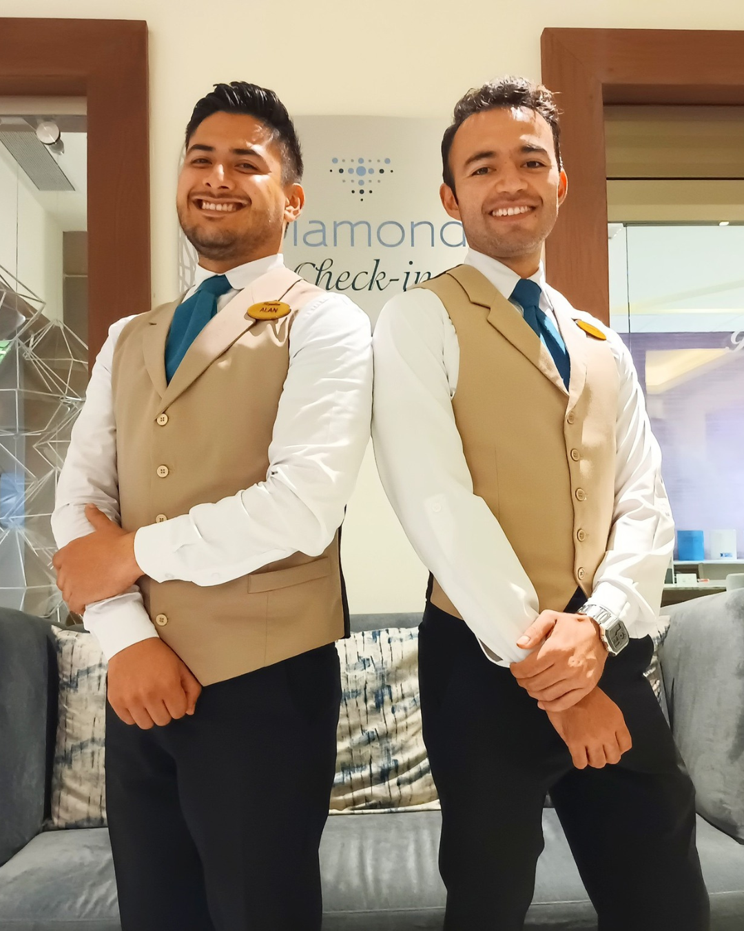 two men in vests standing in front of a window