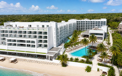 a large white building with a pool and trees around it