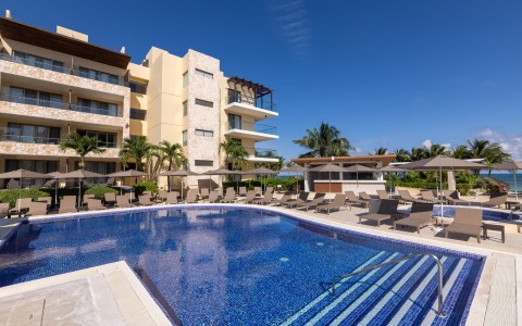 a pool with chairs and umbrellas in front of a building