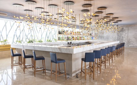 a bar with chairs and lights from the ceiling