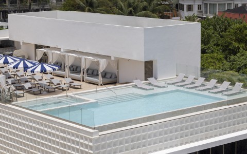 a pool with lounge chairs and umbrellas on a rooftop