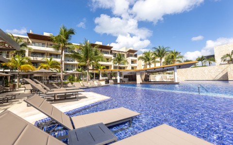 a pool with lounge chairs and palm trees in the background