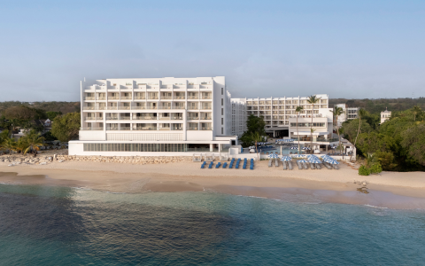 a white building with blue umbrellas and chairs on a beach