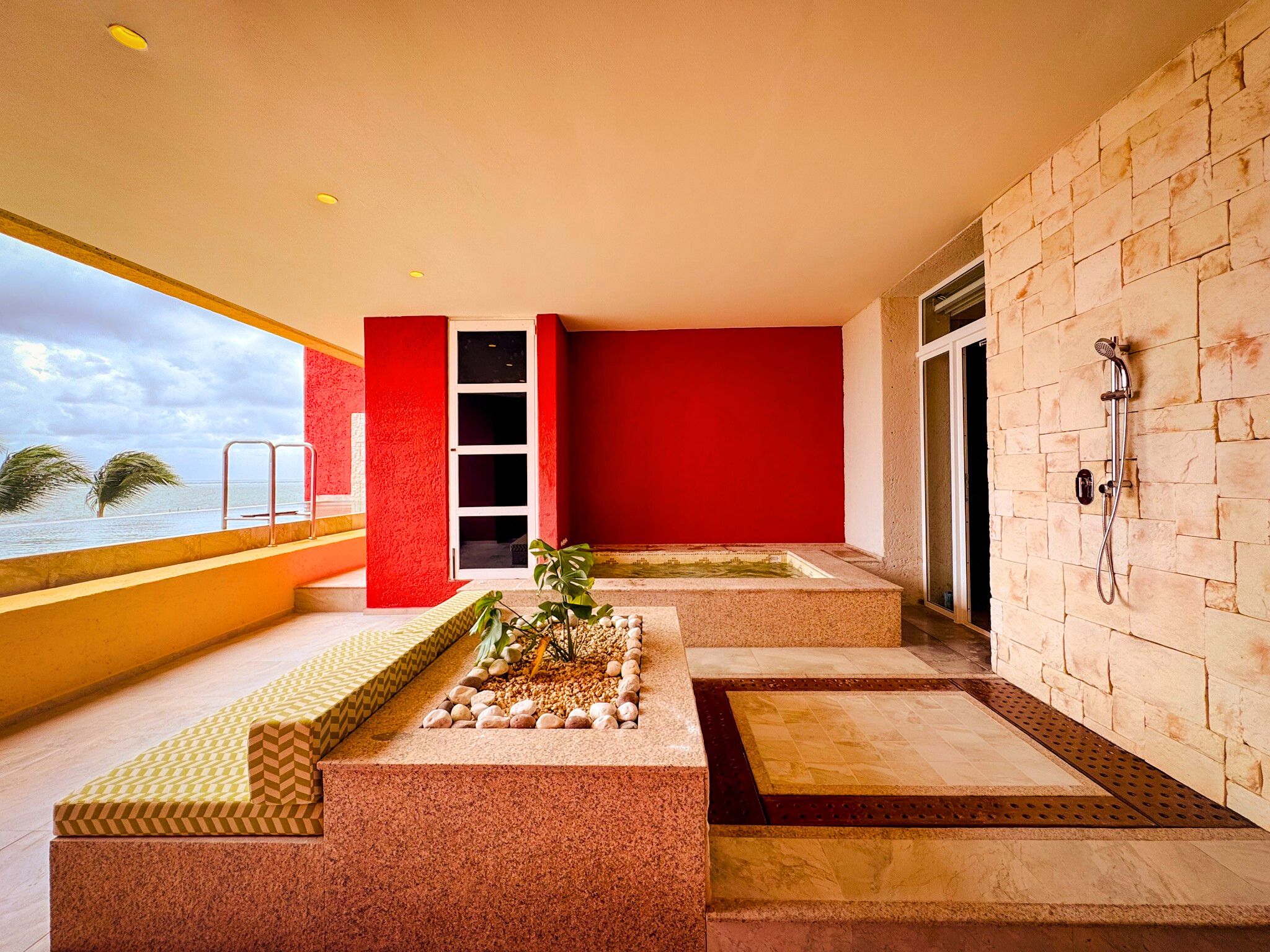 a patio with a water fountain and a red wall