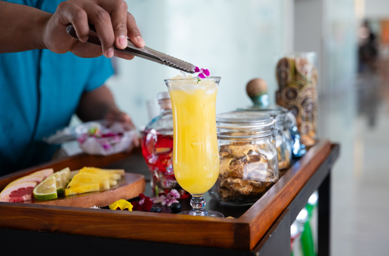 a person holding tongs to a glass of yellow liquid