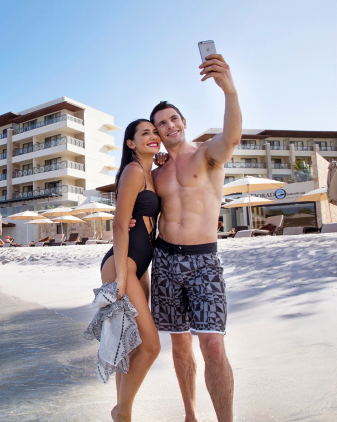 a man and woman taking a selfie on a beach