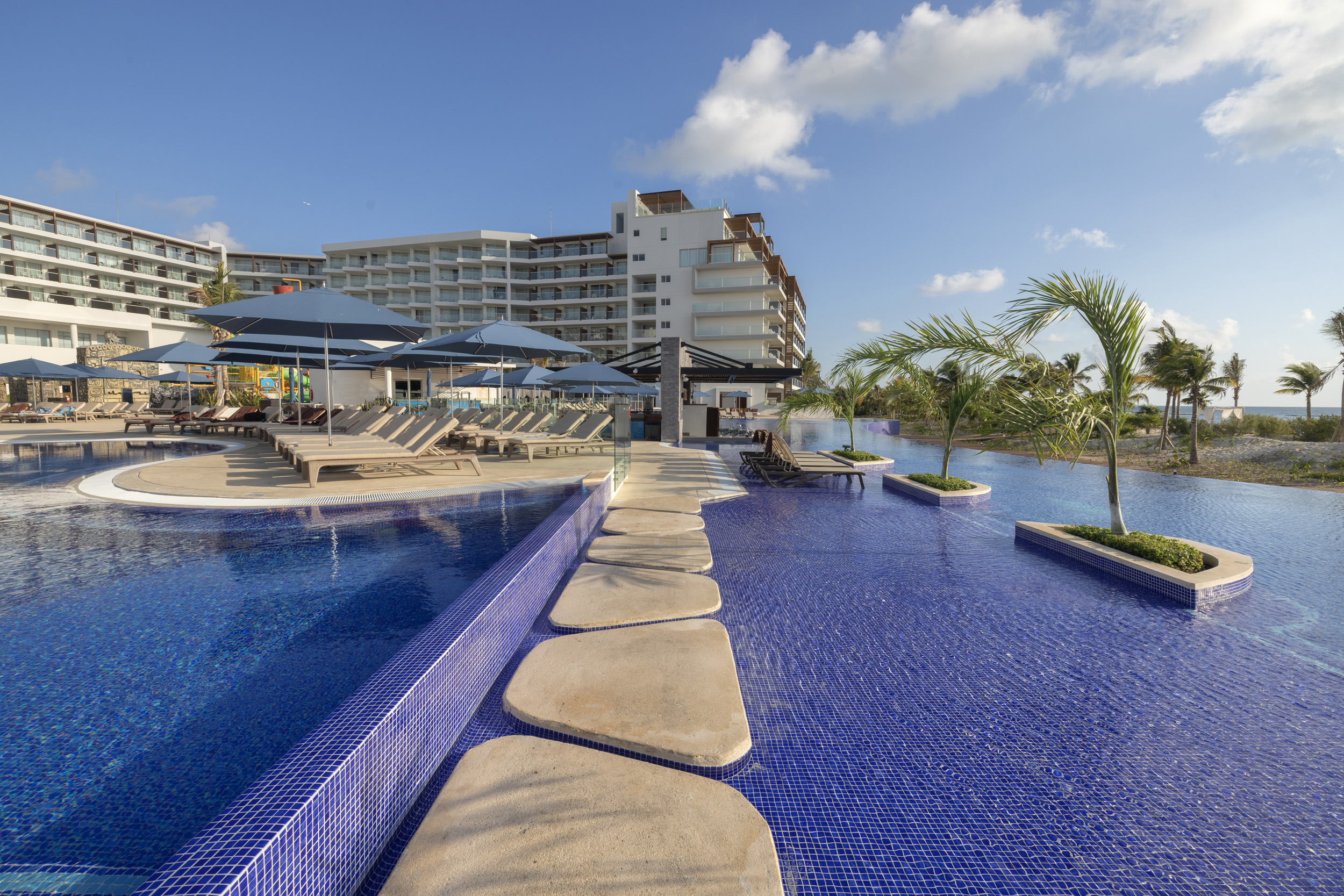 a pool with umbrellas and chairs in front of a building