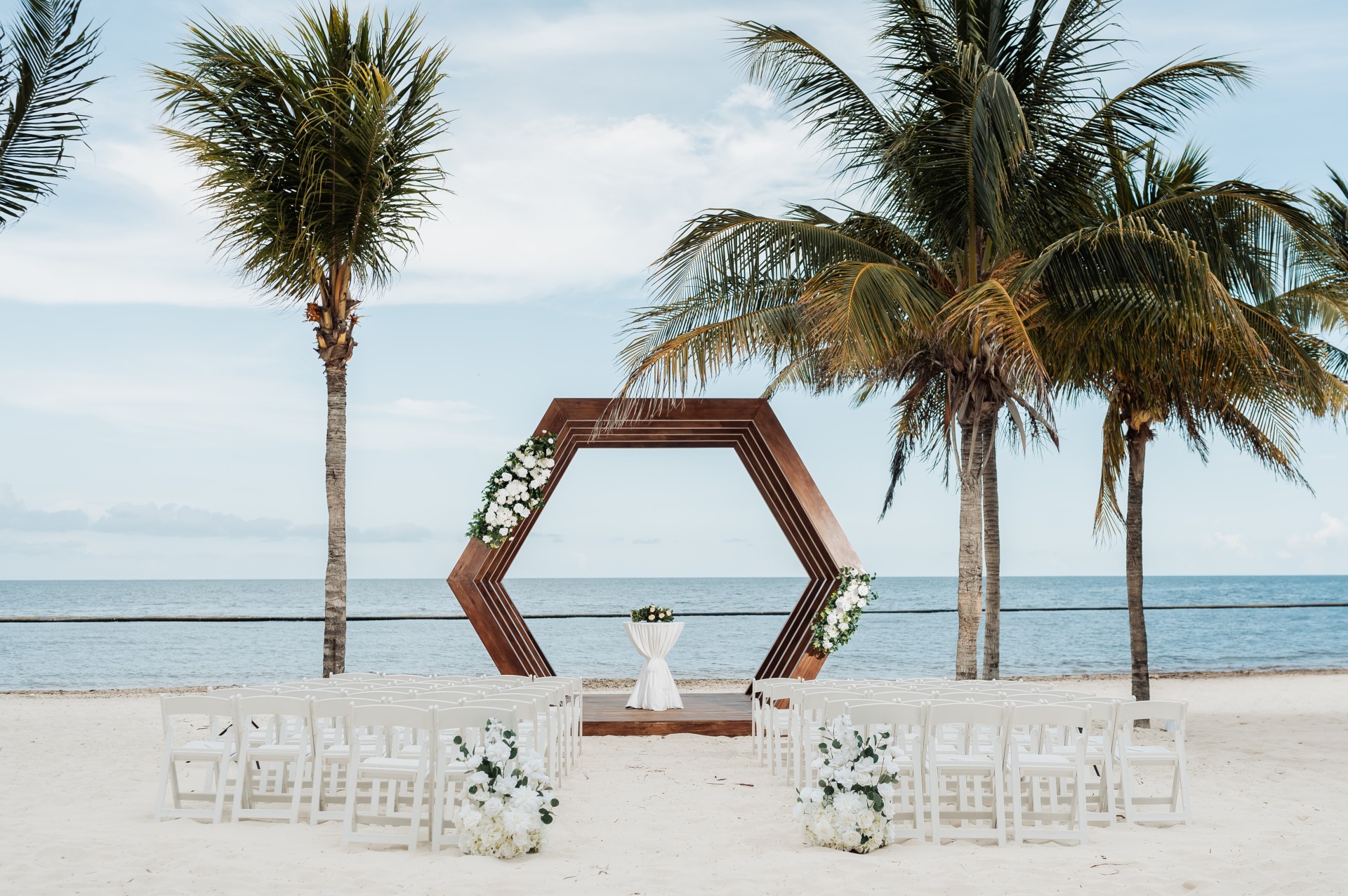 a beach wedding ceremony with chairs and flowers