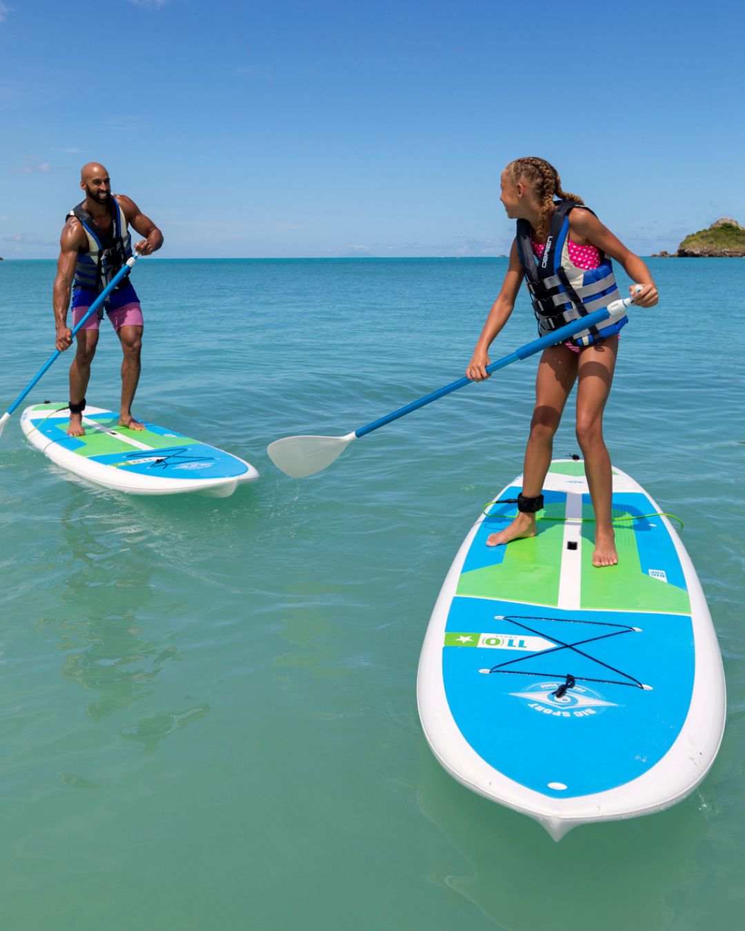 a man and a girl on paddle boards in the water